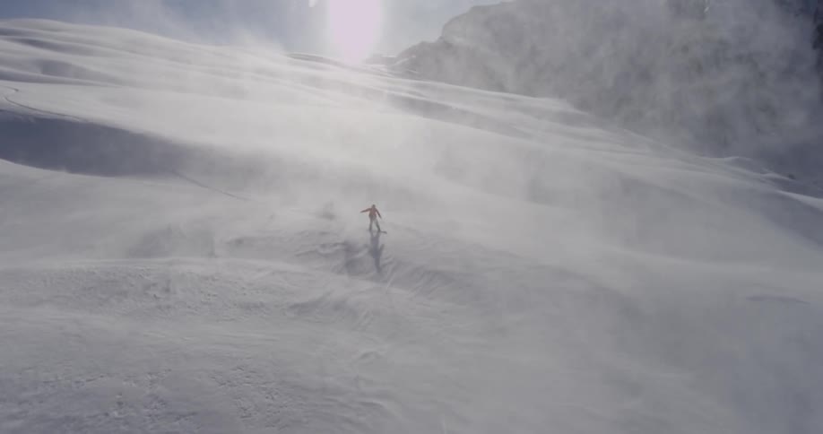 Man snowboarding down a huge snow dune