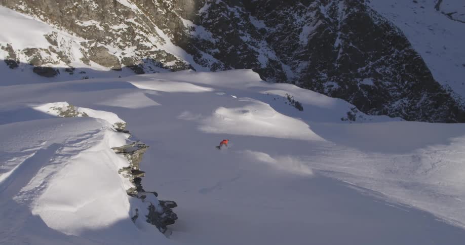 Man snowboarding off a big jump down a mountain