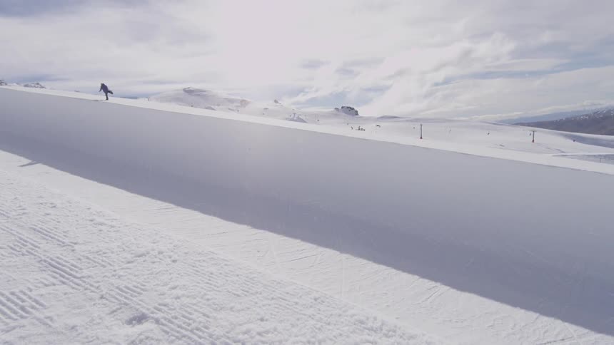 A snowboarder jumps in a half pipe