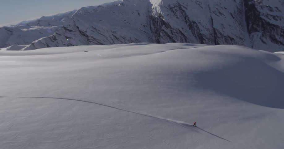 Man traveling by snowboard down a large snow covered field