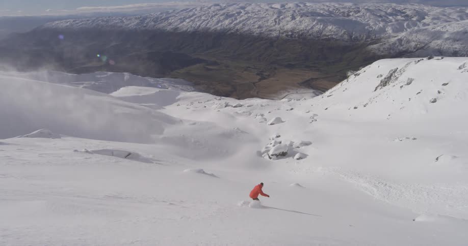 A snowboarder jumping and catching air before landing