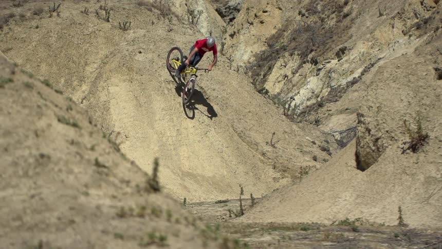 A bicyclist rides over dirt hills