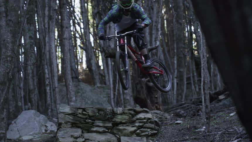 Man riding his bike does a jump as he goes downhill