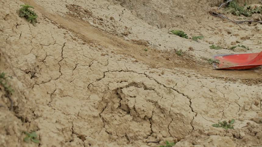 Someone scraping up packed clay dirt with  a shovel