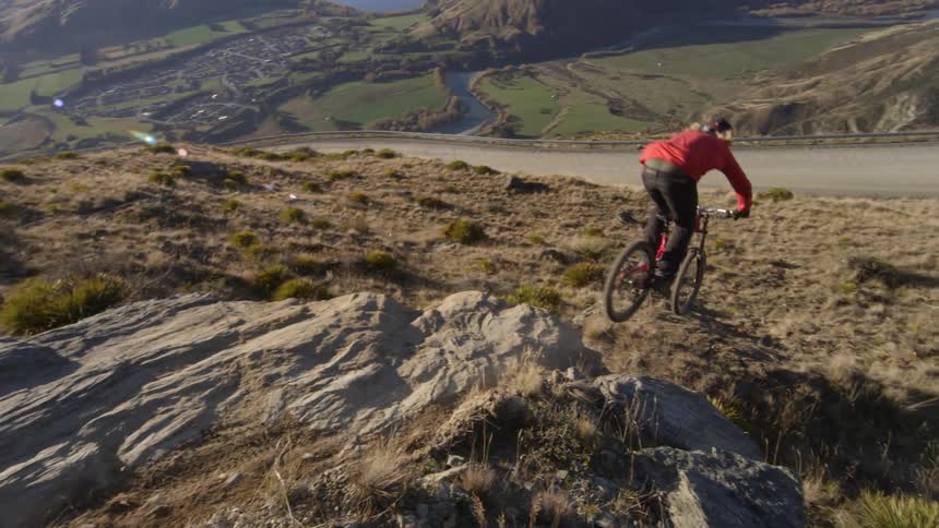 Person riding a dirt bike down a steep rocky path