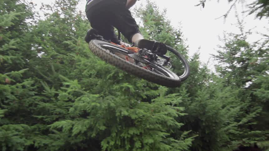 A man is jumping his bike over a gap in the forest