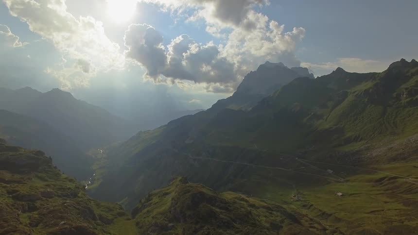 The sun is shining down on a mountain range during the day