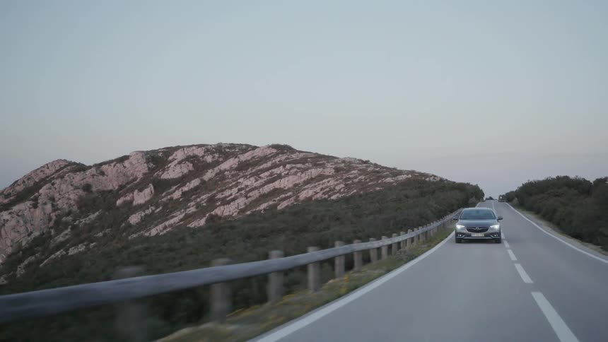 A car is driving on a country road at dusk