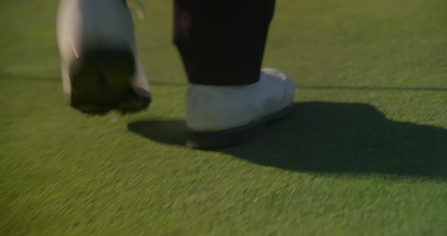 A man walks on the golf course on a sunny day