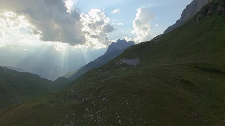 Sun shining behind clouds over mountains