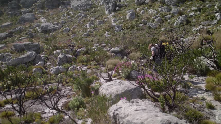 Person wearing a backpack hikes over rocky terrain