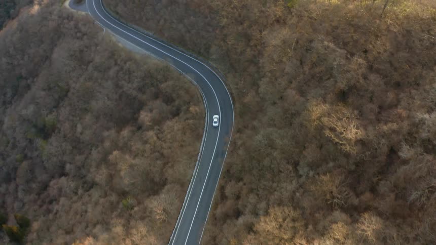 The car drives around the winding road on the hill