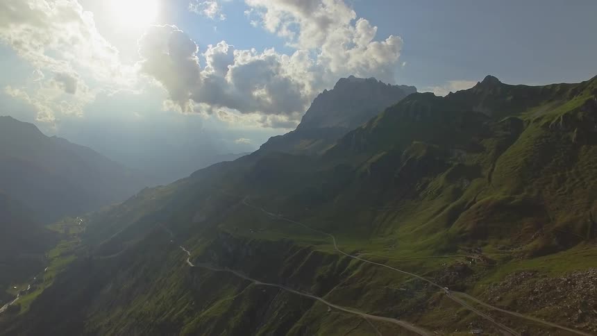 The sun is shining down on a mountain valley during the day