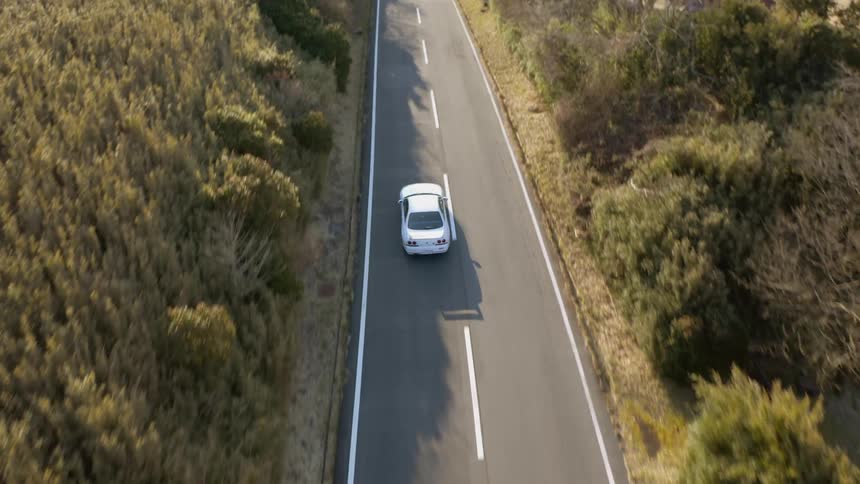 White car drives down a country road on a sunny day