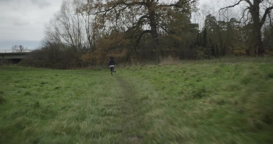 Woman jogs on a path in a field near trees
