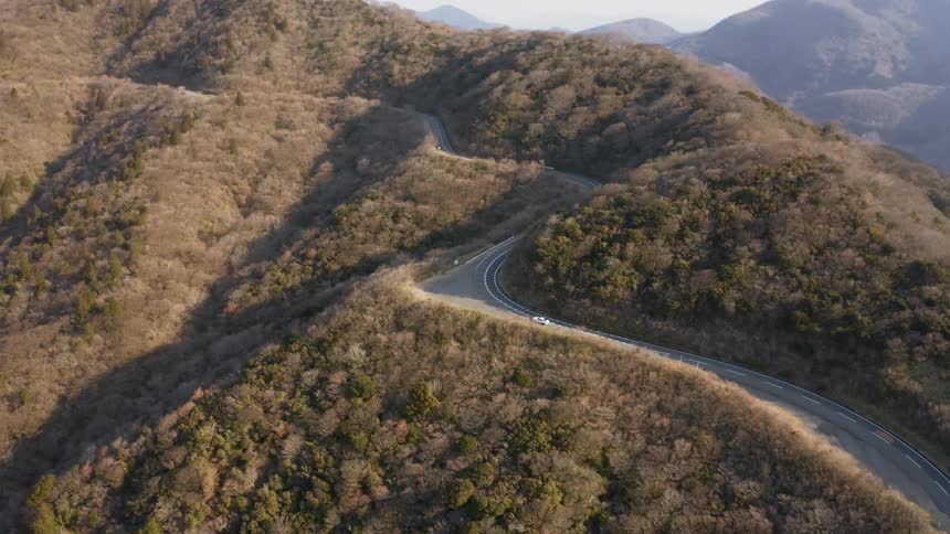 A car travels up the road around the mountain