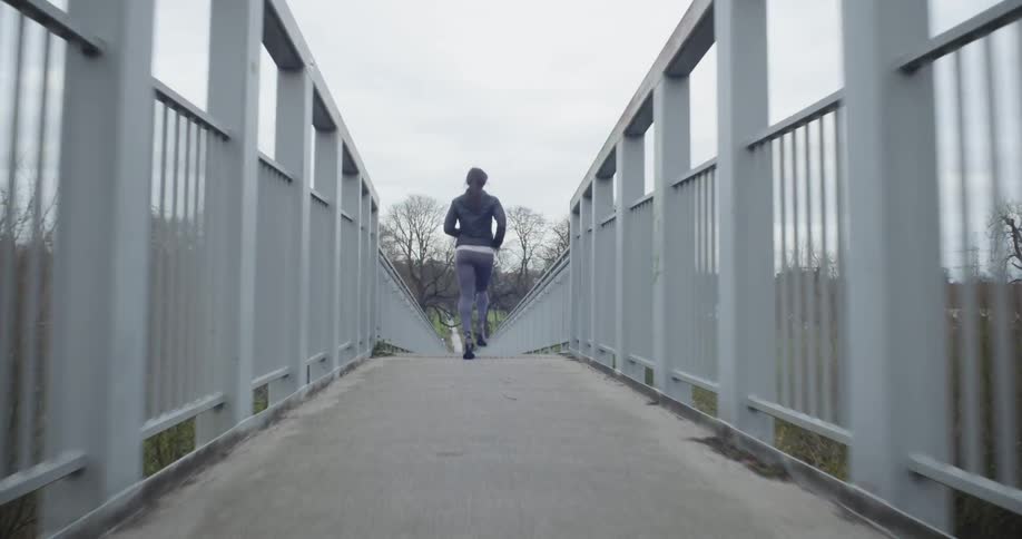Woman jogs on a bridge on a cloudy day