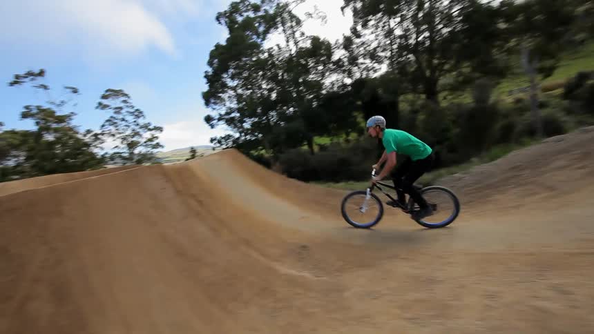 Man jumps his bikes over some hills and does spins