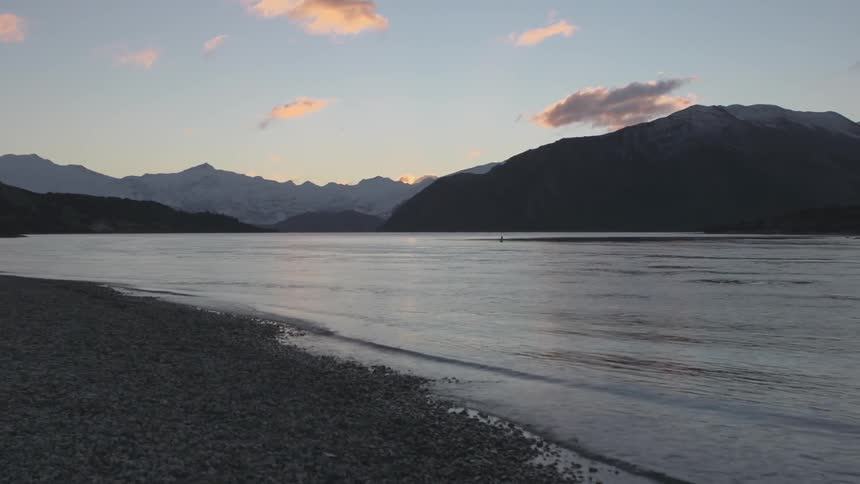 A calm mountain lake and beach at sunset