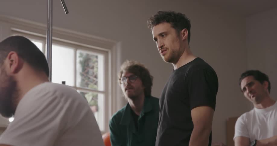 A director and crew watch as a cameraman films inside during the day