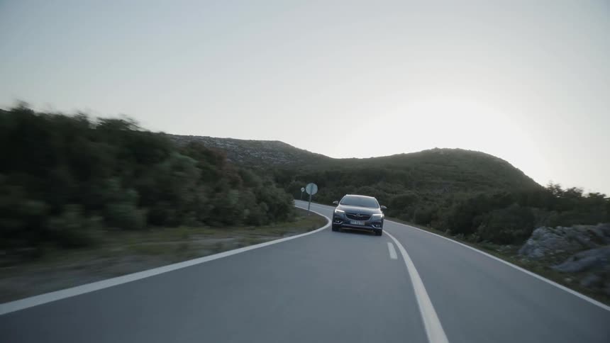 Car drives down a winding country road at sunset