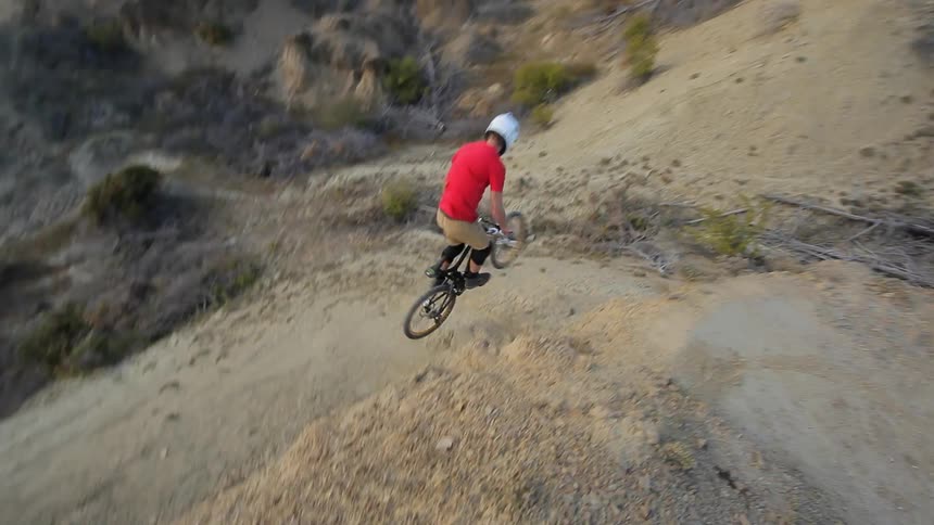 Man does a bike jump off a hill on a mountain