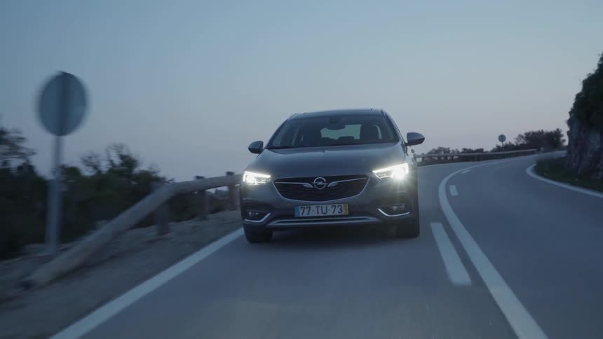 Car drives on a winding country road in the evening
