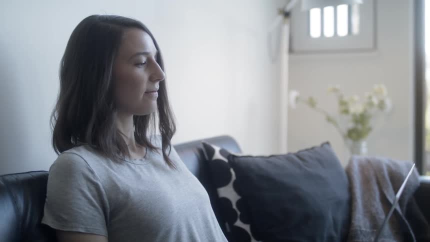Woman sits on a couch near a window
