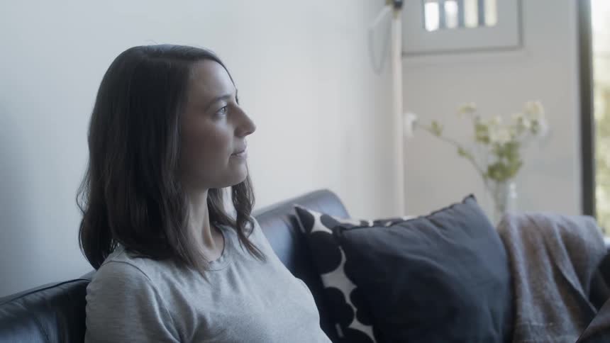 Woman sits on a couch looking out