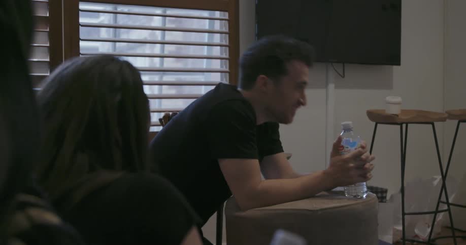 A man laughs and gets up holding a water bottle