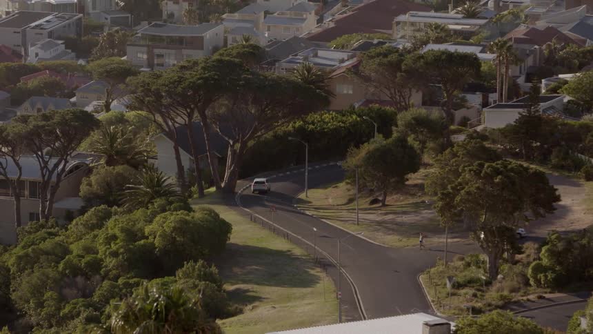 Car drives down a winding road towards a city
