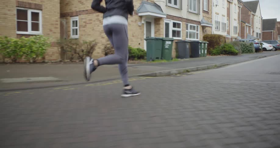 A woman is jogging down the neighborhood street