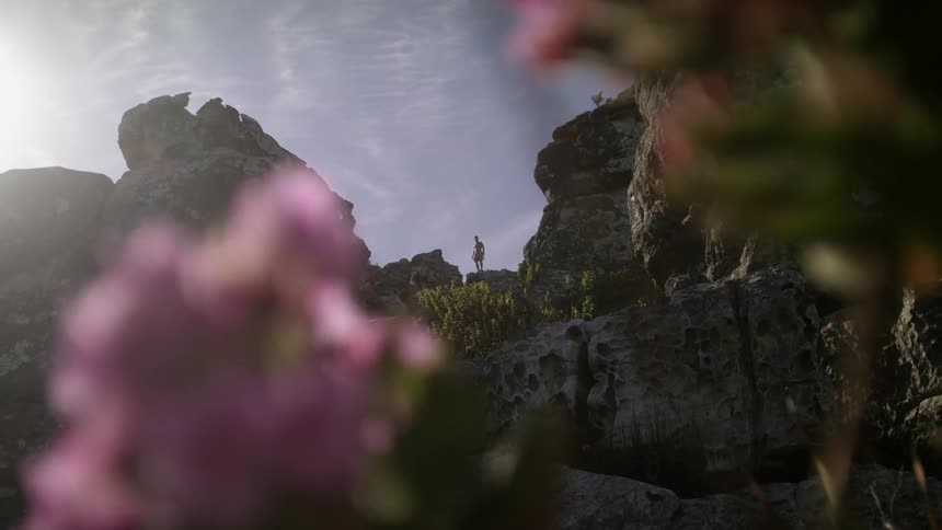 A person stands close to the cliff edge above