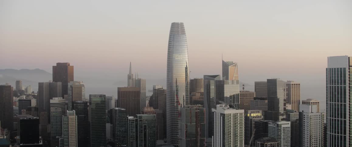 Skyscrapers and high rises in a city are standing tall against a dusk sky