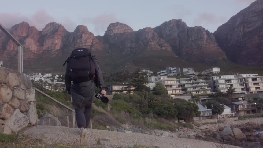 A man carrying a large camera walks out into the wind