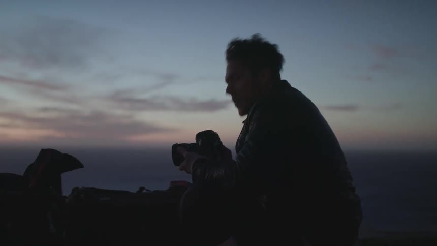Man holds a camera outside at sunset