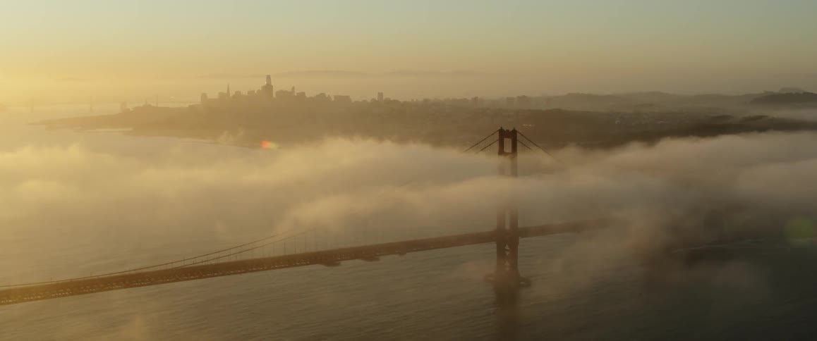 Clouds hover low over a bridge at sunset