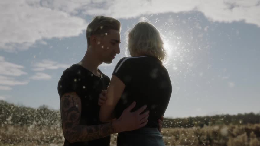 Man and woman hugging in a field with cottonwood floating around