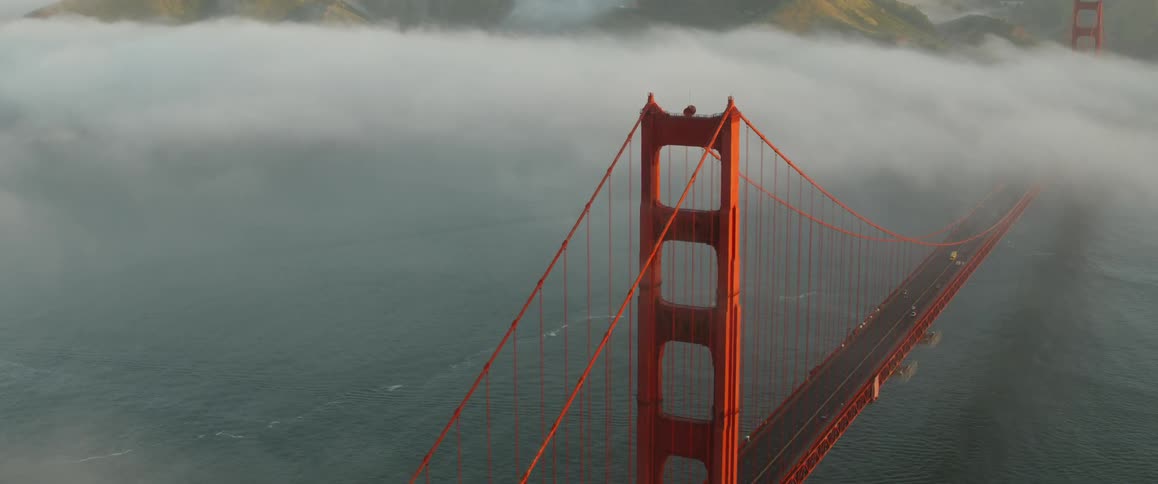 Vehicles travel over the bridge as fog settles in