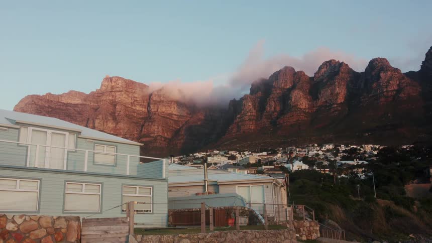 Clouds hang above red mountains above a town