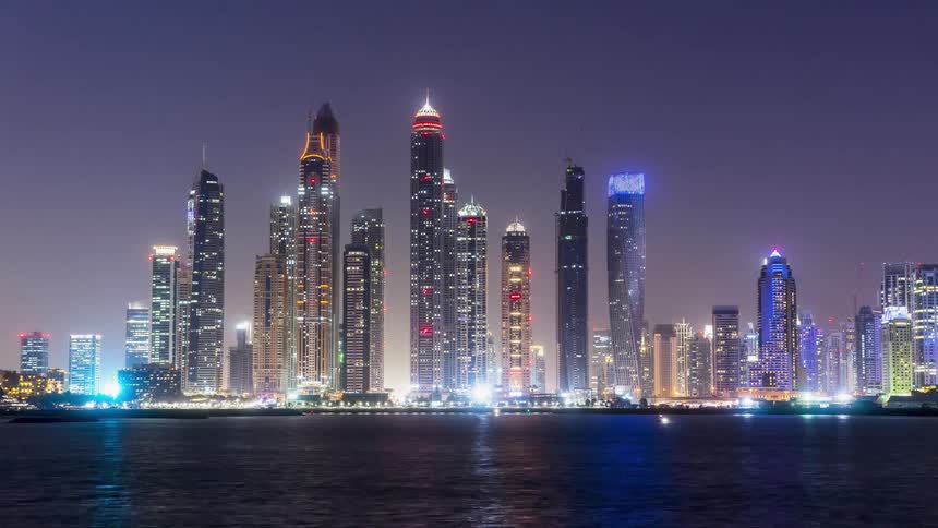 Tall city buildings illuminate the night sky