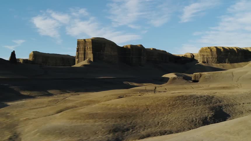 Shadows fall over hilly desert landscape on a sunny day