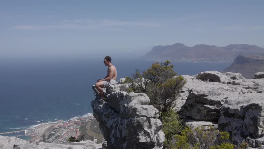 A hiker sits on a cliff edge