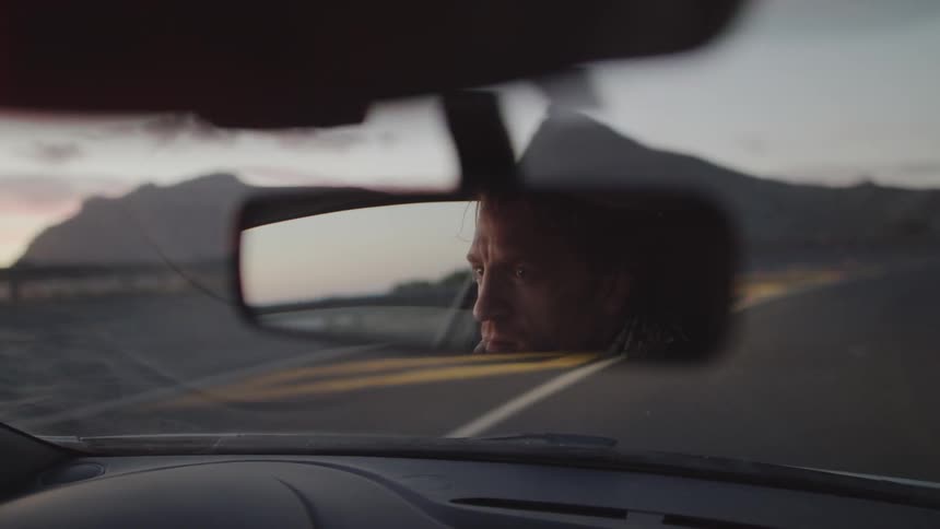 A man is driving around the road at sunset