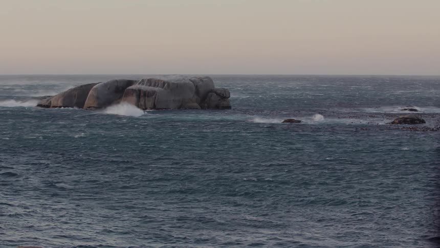 Ocean waves crash into rocks at sunset