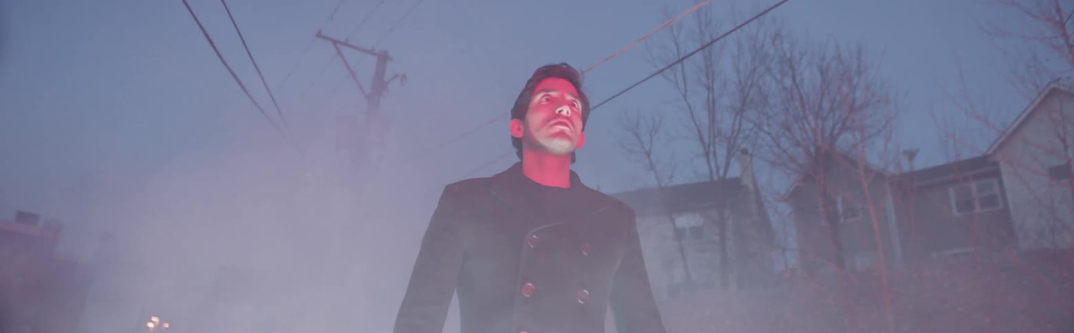 A man stands on a city street at night