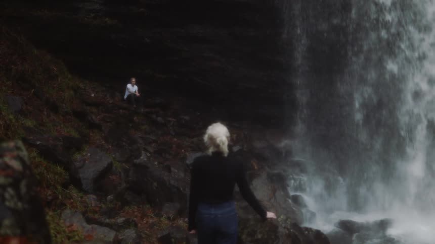 Woman stands near a waterfall