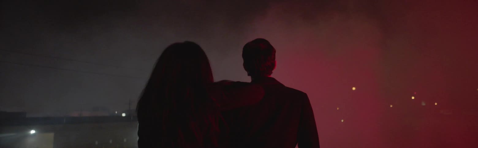 A woman leans on a man outside in the haze