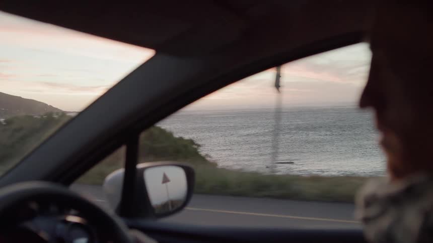 A man drives down the road by the coast