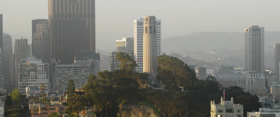 A tower sits before the skyscrapers on the hill